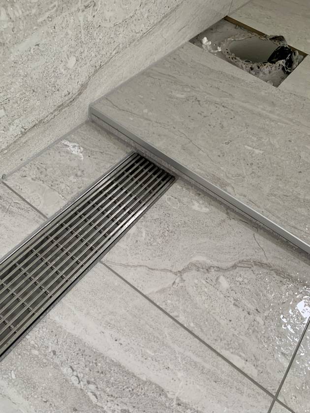 Channel drain: Tiles cut tight to the channel, flush and dead straight.